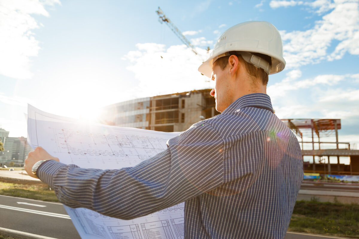 Ingeniero con casco revisando planos en obra de construcción